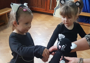 Dwie dziewczynki przebrane za kotki witają się z maskotką - „Kotkiem Psotkiem”